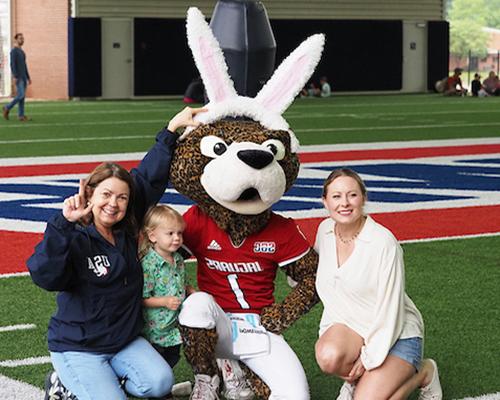 Dr. Paige Vituilli with family and 南paw in bunny ears at easter egg hunt.